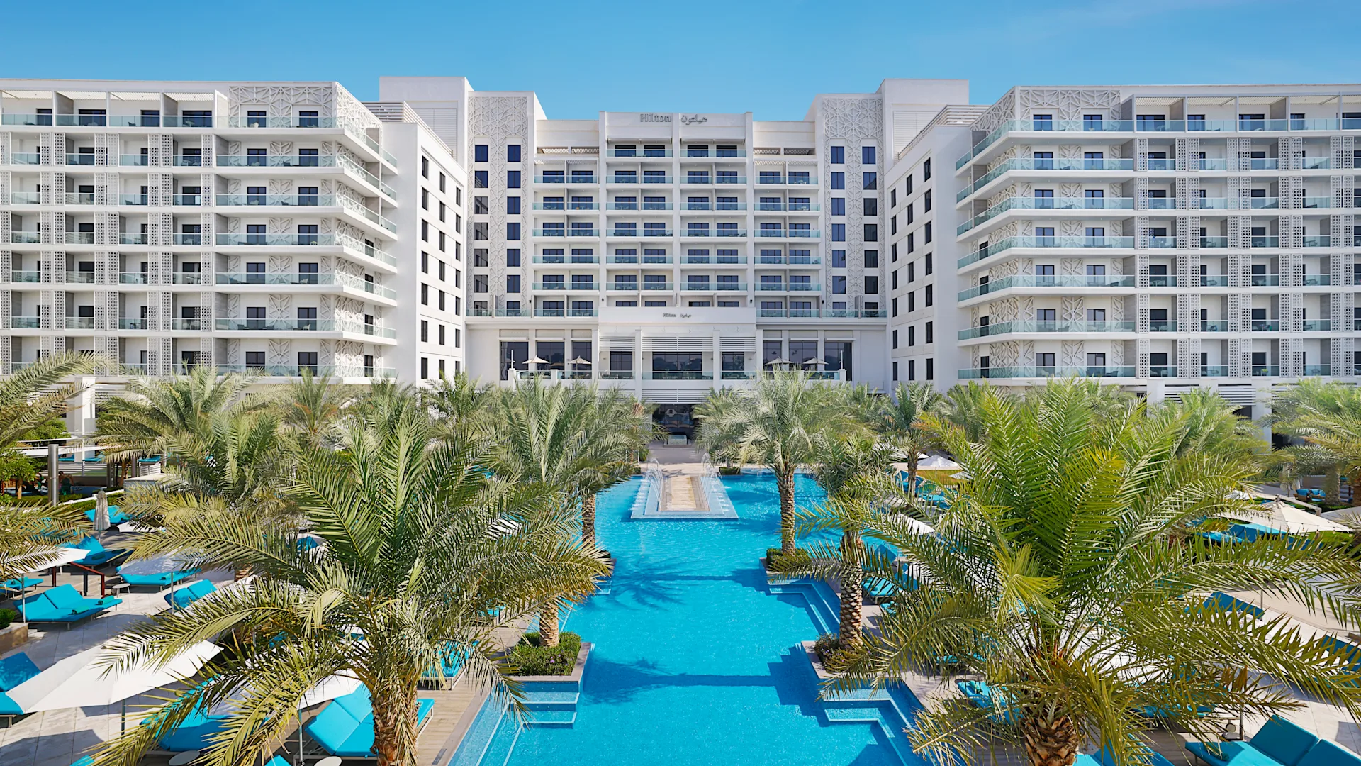 Hilton Yas Island resort pool and palm trees at sunset